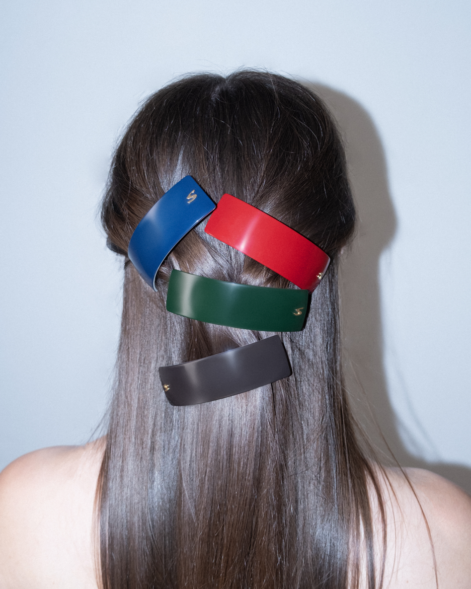 Person with colorful sacrae barrettes hair clips in their hair against a light background